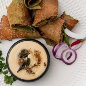 Knusprige Mungbohnen-Dosa, angerichtet auf einem weißen Teller, dazu leckeres Erdnuss-Chetney.