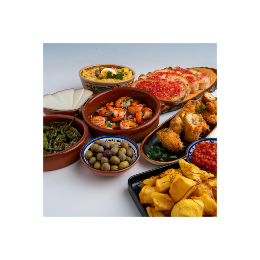 Spanische Tapas-Auswahl mit Garnelen, Patatas Bravas, Pimientos de Padrón, Tomatenbrot, Ensaladilla rusa, croquetas de jamon, Oliven und Manchego-Käse